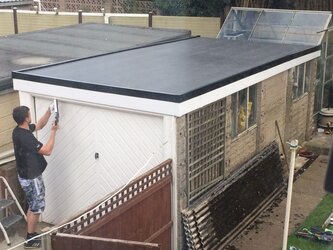 Newly installed flat rubber roof on garage building with clean edges